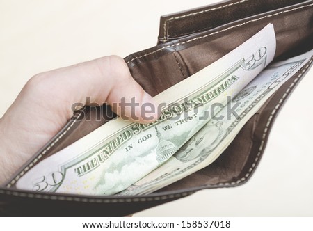 Man holding an open wallet full of money