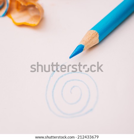 Blue pencil and a small drawing of a spiral