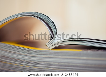 An open magazine sitting on a stack of closed magazines