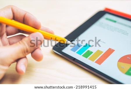 Man pointing out a colorful bar graph on a tablet