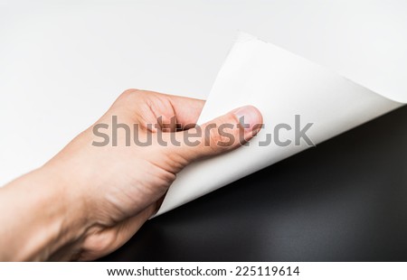 Person turning the white page to reveal a blank dark surface.