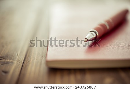 Pen and notebook up close on a rustic wooden desk