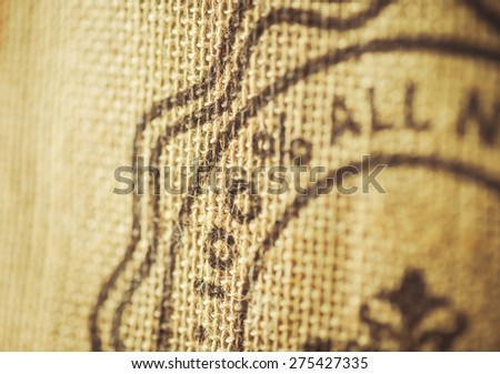 Split toned image of a rustic burlap sack with one hundred percent painted on it
