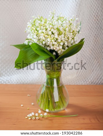 Bouquet of lilies of the valley in glass vase on table