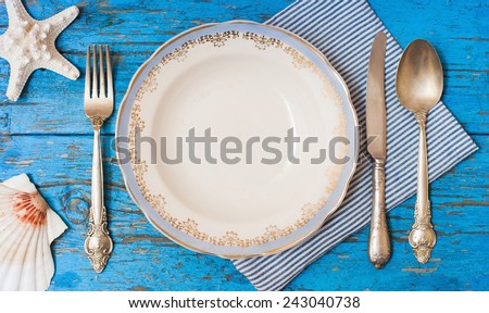 Top view on table setting with vintage silverware with plate on blue wooden table in sea stile