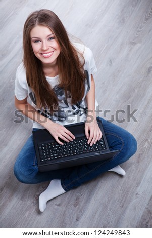 beautiful smiling young woman sitting on the floor using black laptop