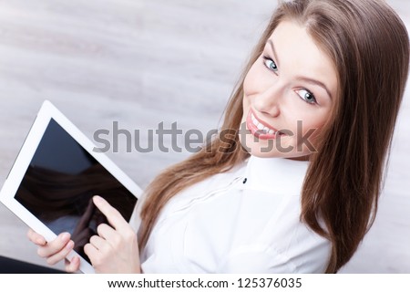Young woman using tablet computer PC wearing white business shirt and smiling into the camera