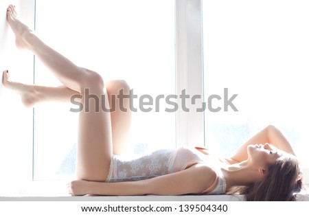 sexy woman in lingerie lying on the window sill. Soft light and colours