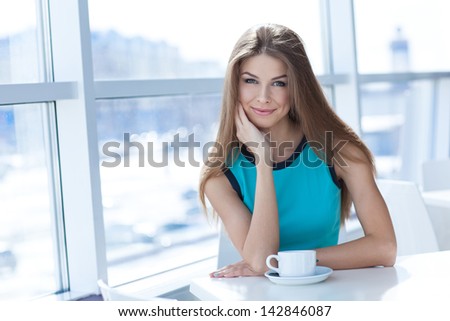 Portrait of a beauty young woman with a tea cup sitting in a coffe shop