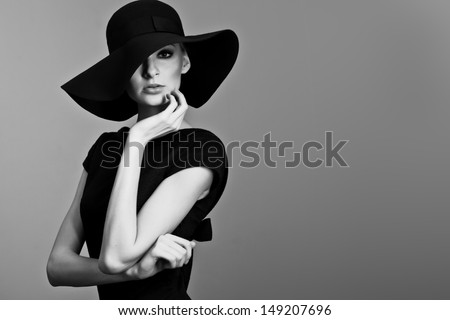 high fashion portrait of elegant woman in black and white hat and dress. Studio shot