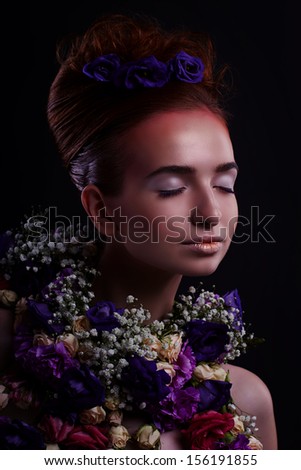 sensual woman with artistic makeup and flowers over dark background
