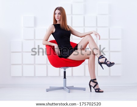 Sexy woman in short black dress sitting on a chair. Fashion shot