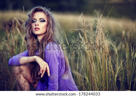 High-fashion portrait of young woman outdoors.Violet dress, bright makeup