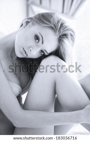 sexy blondy woman in lingerie posing in bedroom.  Soft light and colors. Black and white image