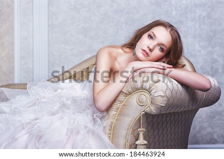 beautiful bride posing in antique sofa, wedding dress, long curly hair