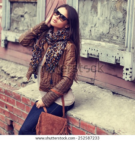 Fashion model with sunglasses, leather jacket, scarf, and handbag