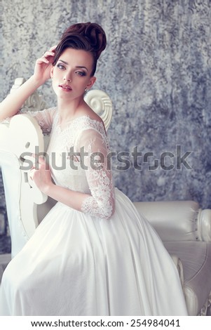 Young gorgeous bride is sitting in antique armchair
