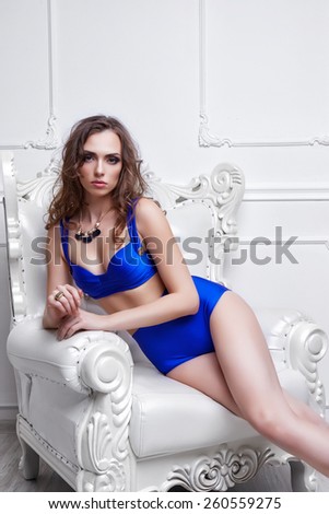 young beautiful woman in blue bikini posing in antique armchair
