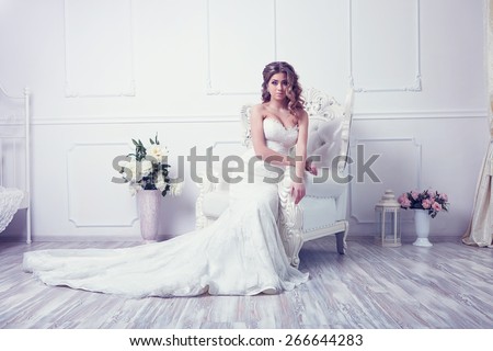 Young beautiful bride is sitting in antique armchair