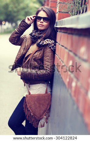 Fashion model with sunglasses, leather jacket, scarf, and handbag