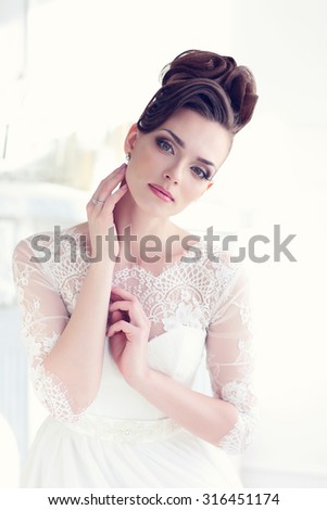 Young gorgeous bride is sitting in antique armchair. Soft light and colours