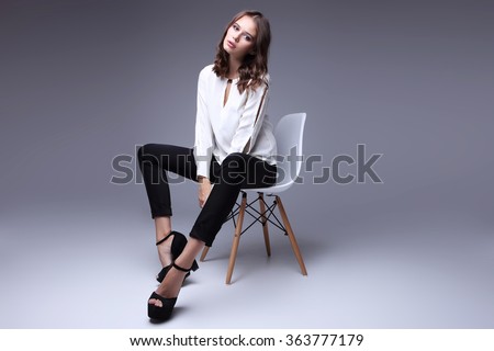 high fashion portrait of young elegant woman. White blouse, black pants, shoes. Studio shot