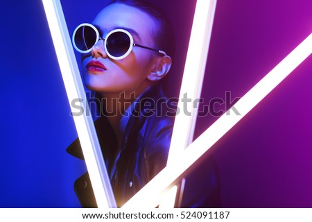 Fashion portrait of young elegant woman in sunglasses. Colored background, studio shot