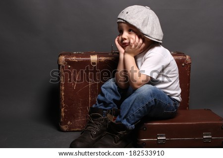 Little boy is sitting on big bag, boredom