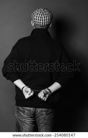 Arrested man handcuffed hands at the back, black and white