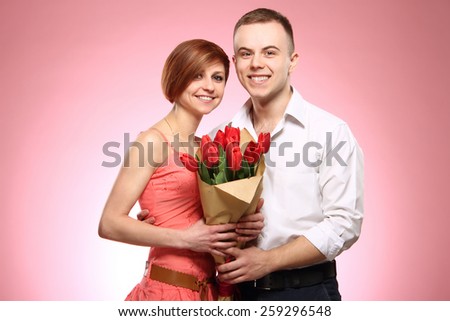 Man surprising his girlfriend with flowers, good emotions , pink background