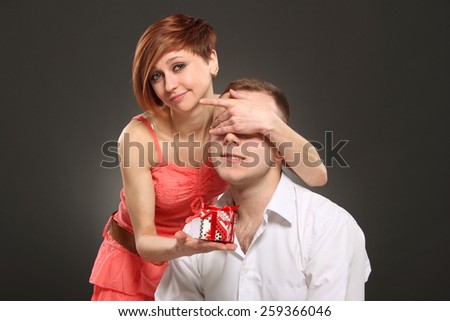 Romantic woman covering her boyfriend\'s eyes. girl standing behind man with gift