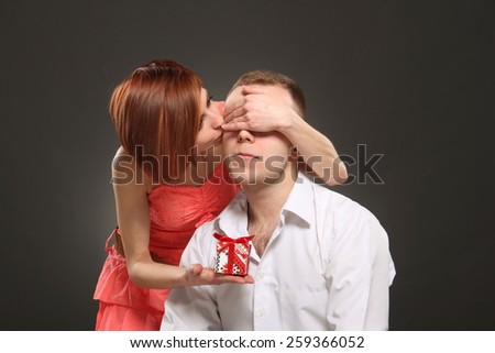 Romantic woman covering her boyfriend's eyes. girl standing behind man with gift