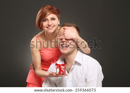 Romantic woman covering her boyfriend\'s eyes. girl standing behind man with gift