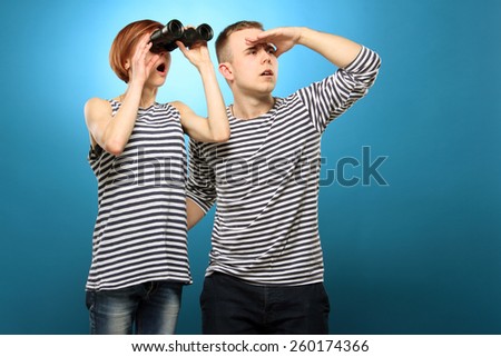Fun couple, emotions. Man and woman  in striped clothing looking through binoculars while standing . Exploring new places.