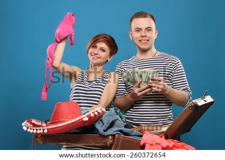 happy couple is going on a trip, pack a suitcase. Woman with bra, man with money