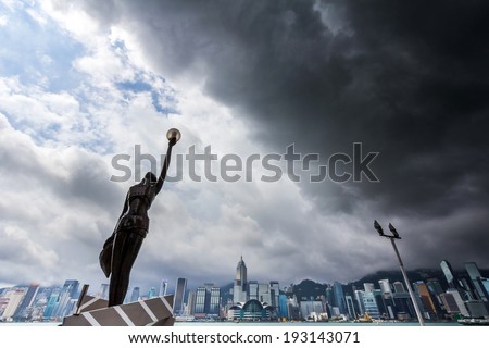 HONG KONG - MAY 15, 2014: Statue and skyline in Avenue of Stars just before a tropical cyclone. Typhoons regularly skirt the city in Summer, causing heavy damages including injuries and deaths.