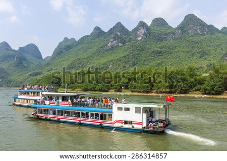 GUILIN, CHINA - MAY 02, 2015: Cruise ship packed with tourists travels the magnificent scenic route along the Lijiang river from Guilin to Yangshou.