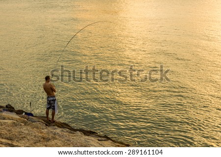 HONG KONG - JUNE 14, 2015: An unidentified person fishing at the rocky shoreline in Sunny Bay Hong Kong.