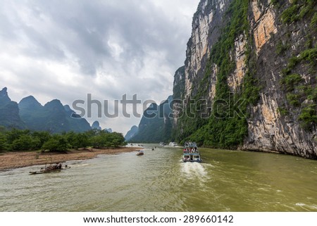 Cruise ship and bamboo rafts travel through the magnificent scenic route along the Li river from Guilin to Yangshou.