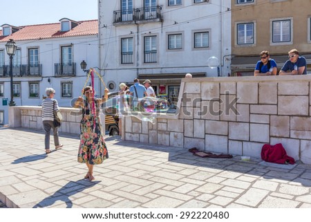 LISBON, PORTUGAL - MAY 27, 2015: A person entertain the crowd gathered at Largo das Portas do Sol in Lisbon Portugal. Outdoor entertainment is the part of European culture.