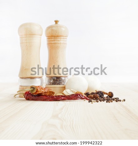 Wooden pepper-mills on table isolated over white.