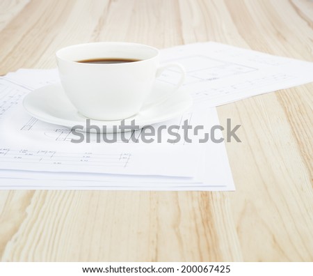 Architectural office desk with blueprints and coffe cup.