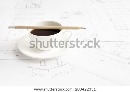 Architectural office desk with blueprints and coffe cup.