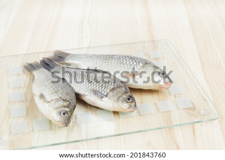 Fresh sea fish on glass cutting board.