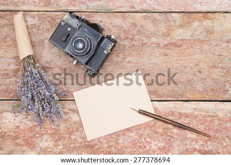 Top view on work place with flowers, paper and photo camera.