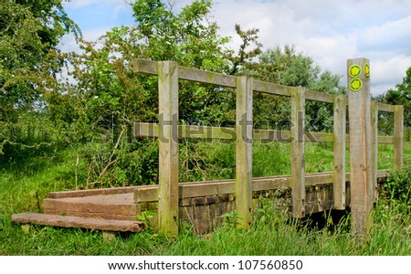 Close crop of bridge in the English Countryside showing Public Footpath signs over a little beck on a summers day