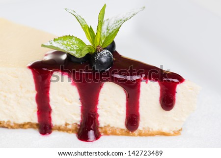 Dessert - Cheesecake  with black currant sauce and green mint .