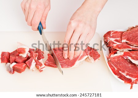Chef chopping a meat with a knife on the cutting board