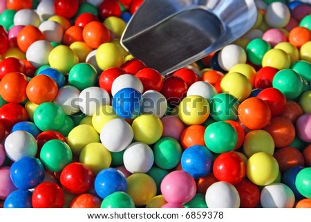 Assortment of multicolored round bonbons in a barrel accompanied with a scoop to be picked out on a market.