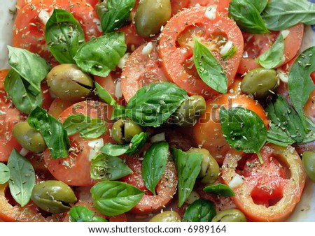 Typical salad of Southern Italy: tomatoes, basil torn manually, garlic, dry oregano, and pressed green olives